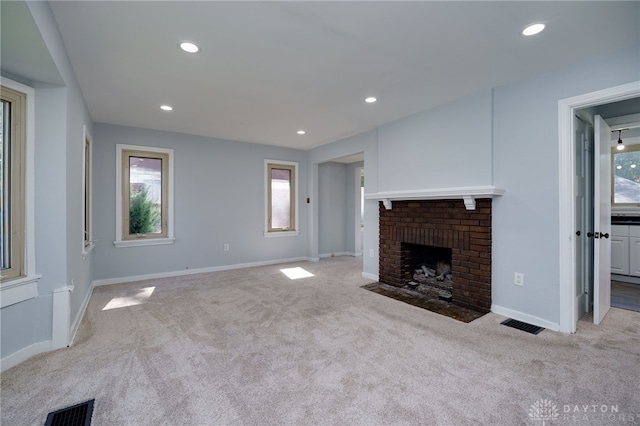 unfurnished living room with light carpet and a brick fireplace