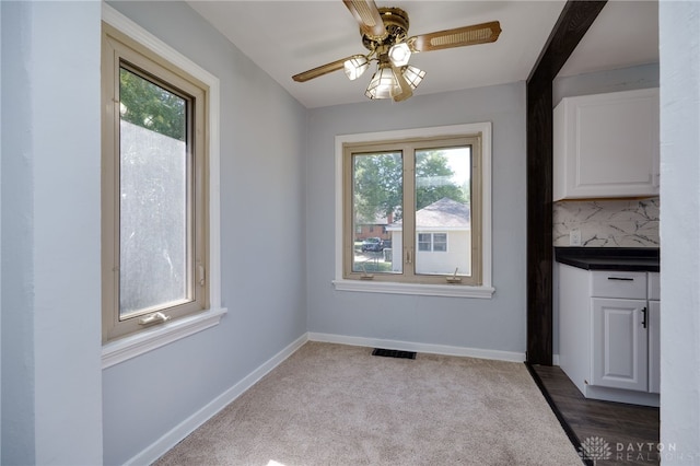 unfurnished dining area with light colored carpet and ceiling fan