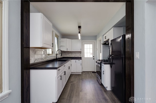 kitchen featuring stainless steel gas range oven, white cabinets, black refrigerator, sink, and decorative backsplash