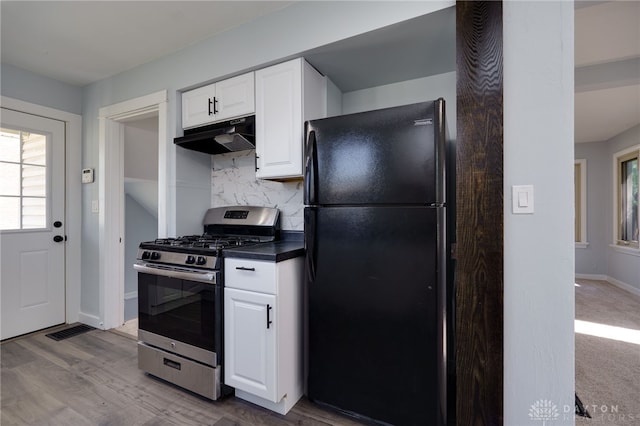 kitchen featuring tasteful backsplash, black fridge, light hardwood / wood-style flooring, stainless steel gas stove, and white cabinetry