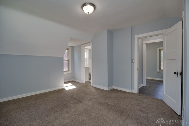 additional living space with dark carpet and lofted ceiling