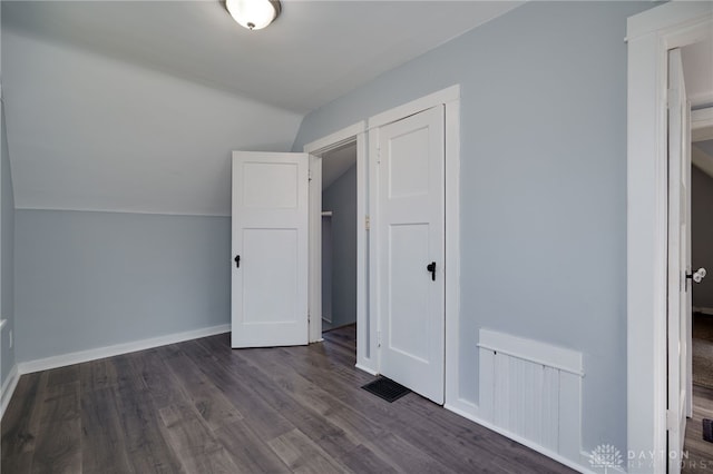 additional living space featuring dark wood-type flooring and vaulted ceiling