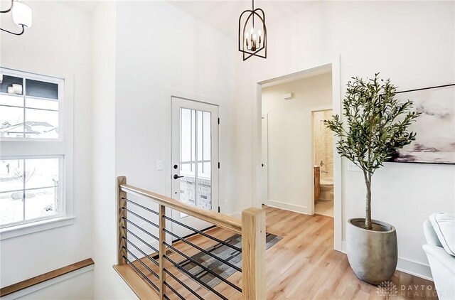 foyer with light wood-type flooring, a towering ceiling, and a chandelier