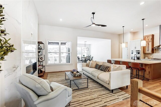 living room with ceiling fan, light hardwood / wood-style floors, and sink