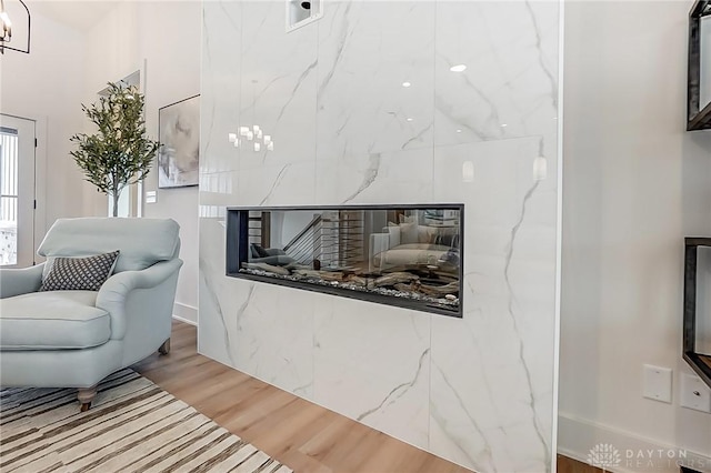 living area featuring wood-type flooring and a tiled fireplace