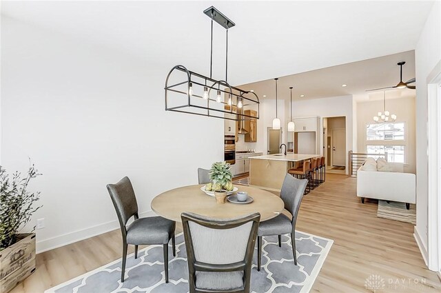 dining room featuring ceiling fan, light wood-type flooring, and sink