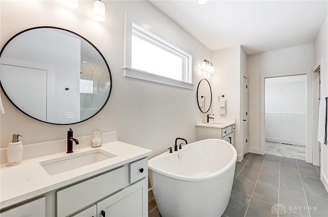 bathroom with tile patterned floors, a washtub, and vanity