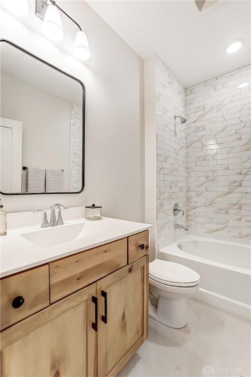 full bathroom with vanity, tiled shower / bath combo, and toilet