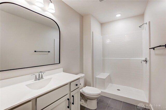 bathroom featuring a shower, vanity, tile patterned flooring, and toilet