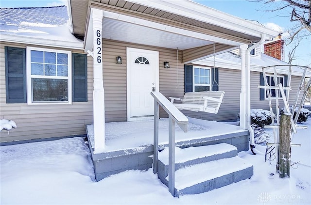 snow covered property entrance featuring a porch