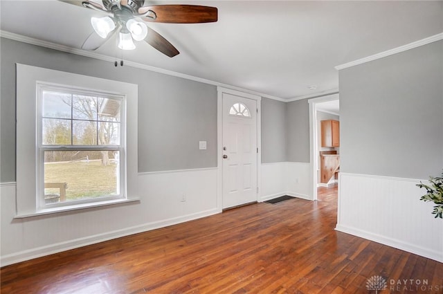 spare room featuring dark wood-style floors, a wainscoted wall, crown molding, and ceiling fan