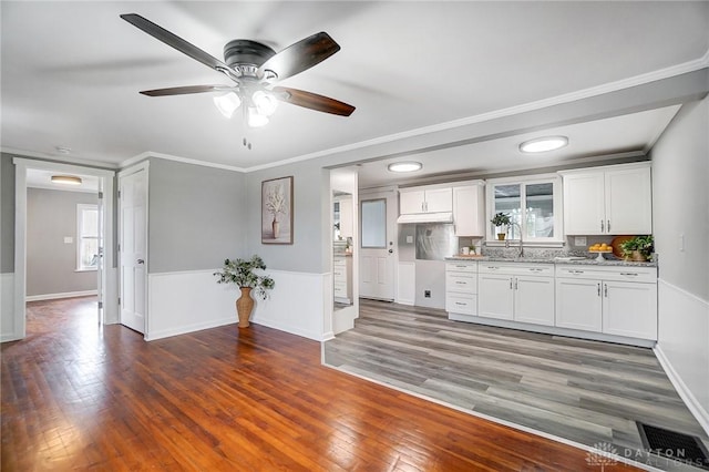 kitchen with crown molding, light stone counters, dark wood-type flooring, and white cabinets