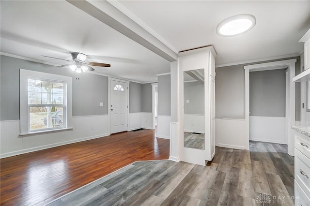 foyer entrance featuring wood finished floors, crown molding, and wainscoting