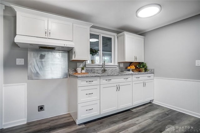 kitchen with white cabinets, a sink, under cabinet range hood, and light stone countertops