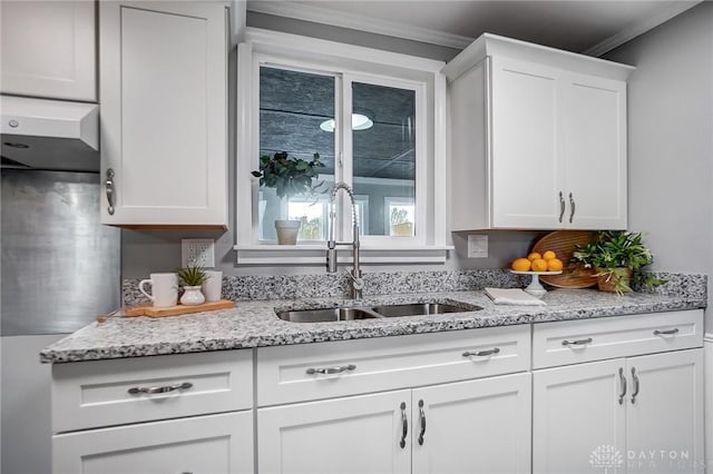 kitchen with light stone countertops, white cabinets, and a sink