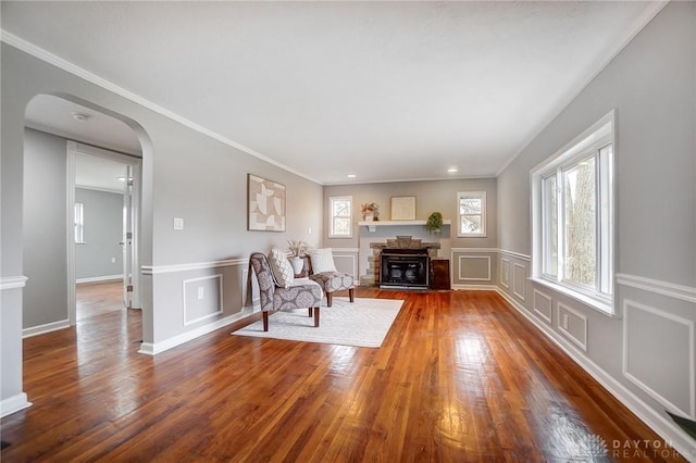 unfurnished room with a fireplace, arched walkways, a decorative wall, and dark wood-type flooring