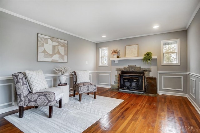 sitting room featuring a fireplace, ornamental molding, a decorative wall, and wood finished floors