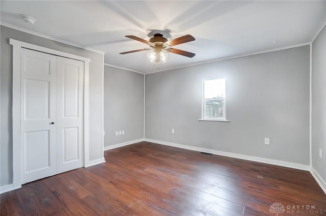 unfurnished bedroom with dark wood-type flooring, ornamental molding, and baseboards