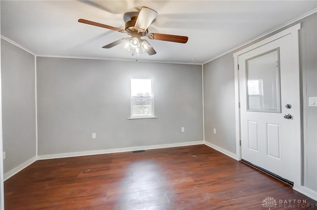 empty room with dark wood-style floors, visible vents, ornamental molding, ceiling fan, and baseboards