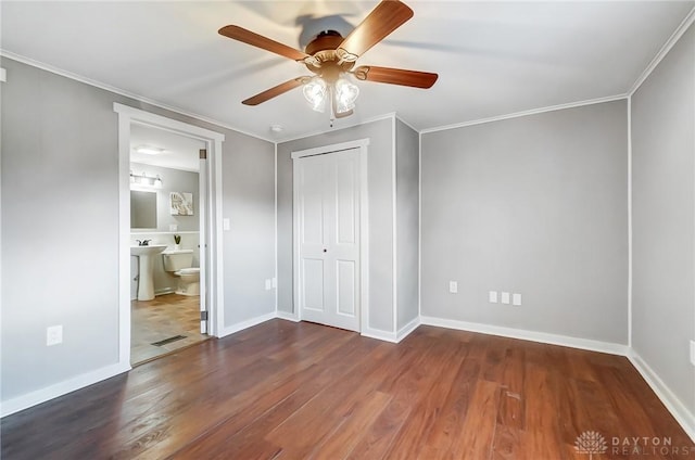 unfurnished bedroom featuring a closet, baseboards, dark wood-type flooring, and crown molding