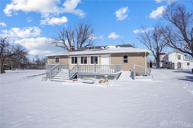 snow covered back of property with a chimney