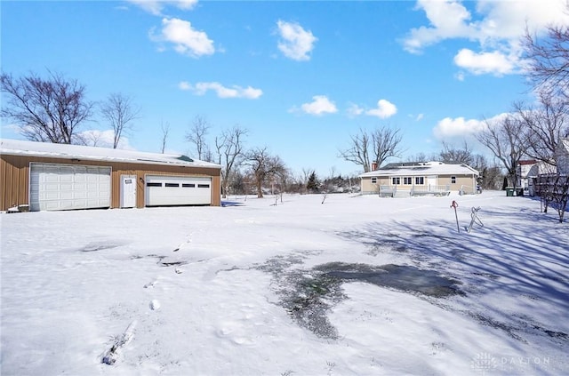 yard covered in snow featuring a detached garage