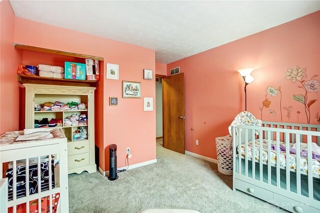 carpeted bedroom featuring a nursery area