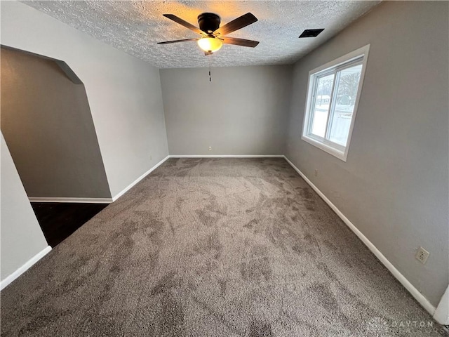 unfurnished room with dark colored carpet, ceiling fan, and a textured ceiling