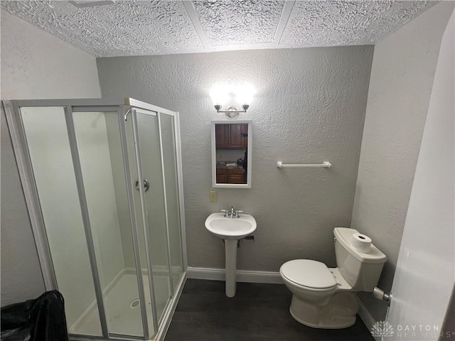 bathroom featuring a shower with shower door and toilet