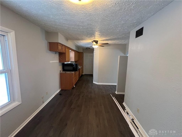 corridor with a textured ceiling and dark wood-type flooring