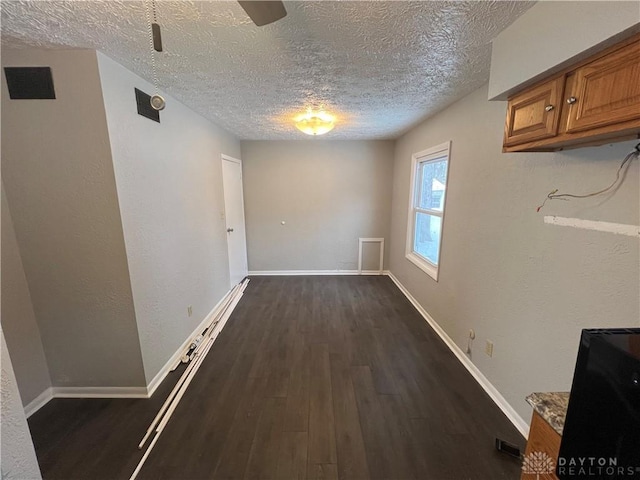 unfurnished dining area featuring dark wood-type flooring and a textured ceiling