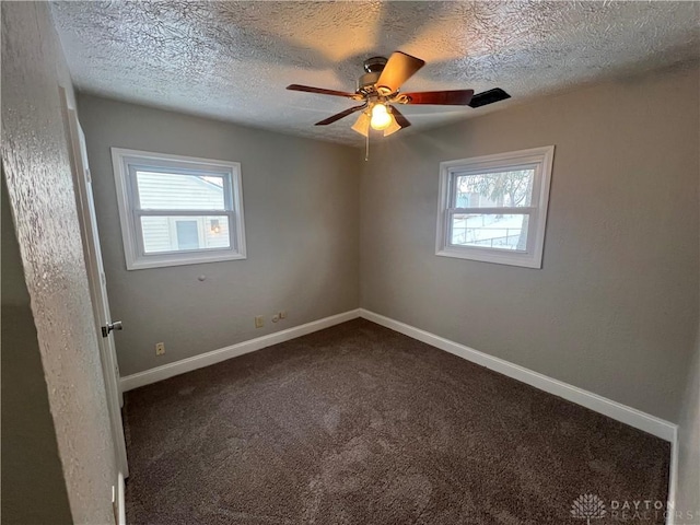 carpeted spare room featuring ceiling fan, a textured ceiling, and a wealth of natural light