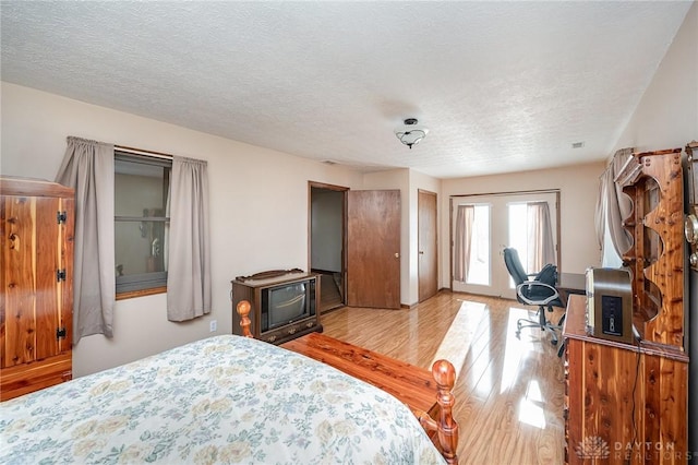 bedroom featuring light wood finished floors, access to outside, and a textured ceiling