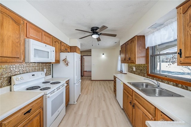 kitchen featuring white appliances, light countertops, a sink, and brown cabinetry