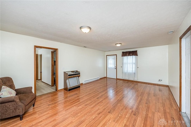 sitting room featuring a textured ceiling, a baseboard radiator, visible vents, and light wood-style floors