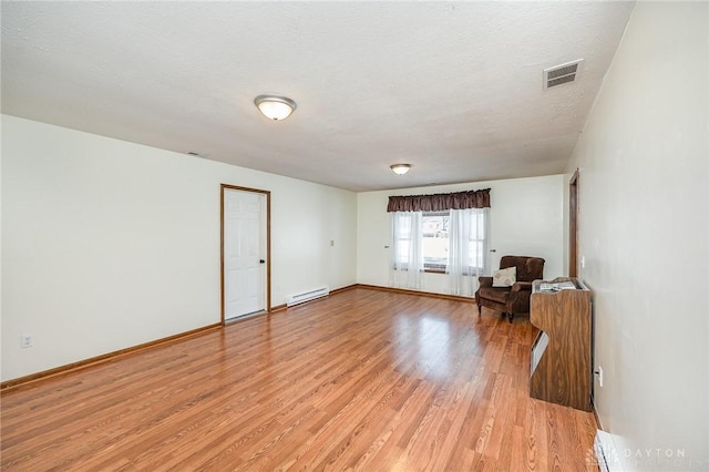 unfurnished room featuring baseboards, visible vents, a baseboard radiator, light wood-style flooring, and a textured ceiling