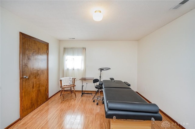 exercise area with visible vents, baseboards, and wood finished floors