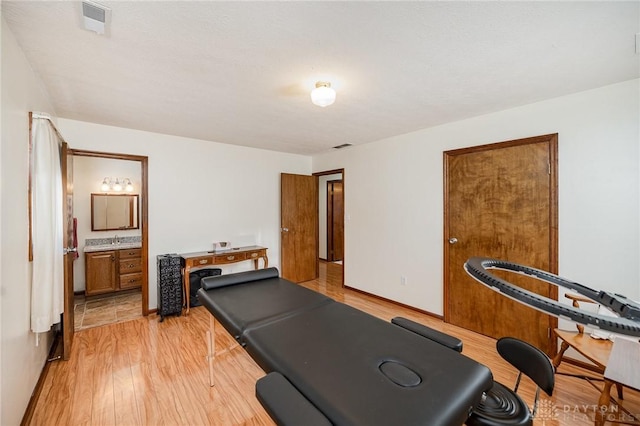 exercise area with light wood-style floors, a sink, and baseboards