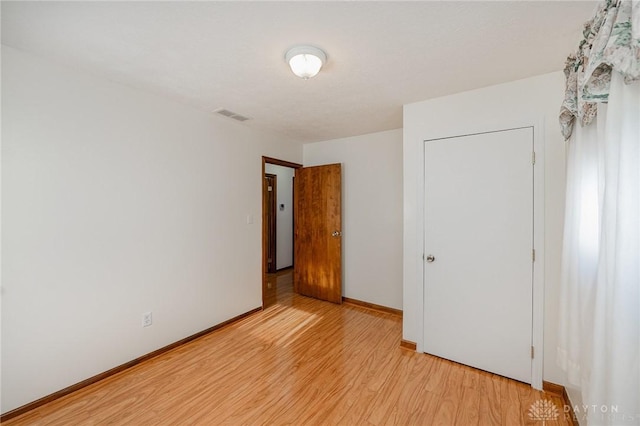 unfurnished bedroom with light wood-type flooring, visible vents, and baseboards