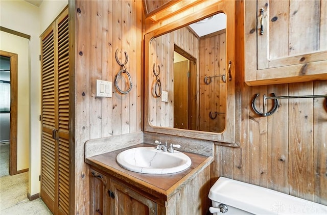 bathroom featuring vanity, toilet, and wooden walls