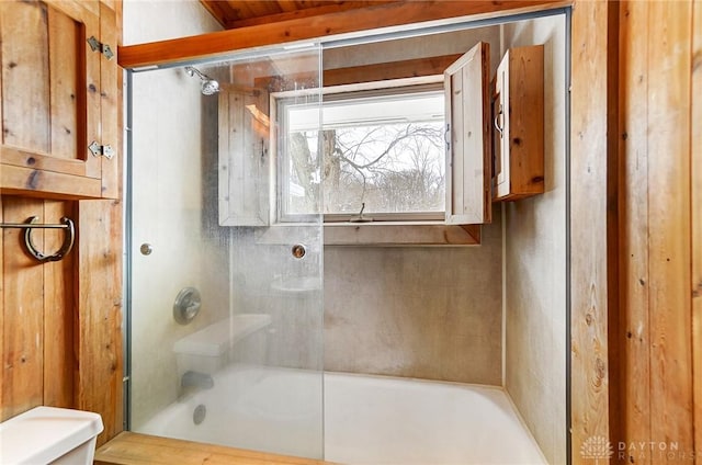 bathroom featuring combined bath / shower with glass door and toilet