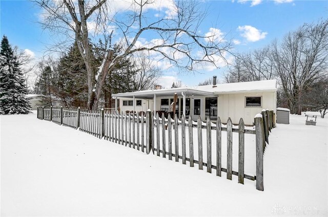 snow covered back of property with covered porch