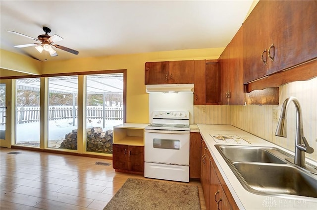 kitchen featuring white range with electric stovetop, ceiling fan, light wood-type flooring, and sink