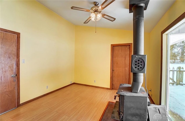 interior space with ceiling fan, a wood stove, and light hardwood / wood-style flooring