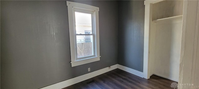 unfurnished bedroom featuring multiple windows and dark wood-type flooring