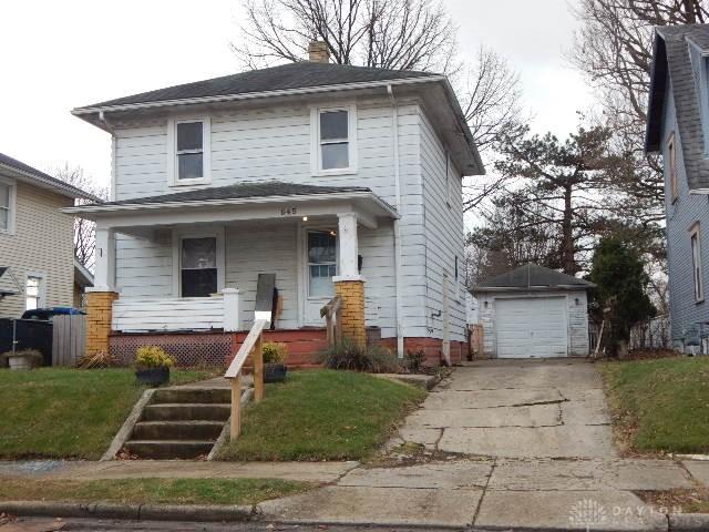 traditional style home with an outbuilding, a front yard, driveway, covered porch, and a chimney