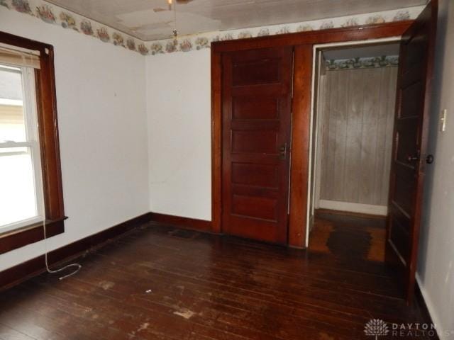 spare room featuring baseboards and dark wood-style flooring