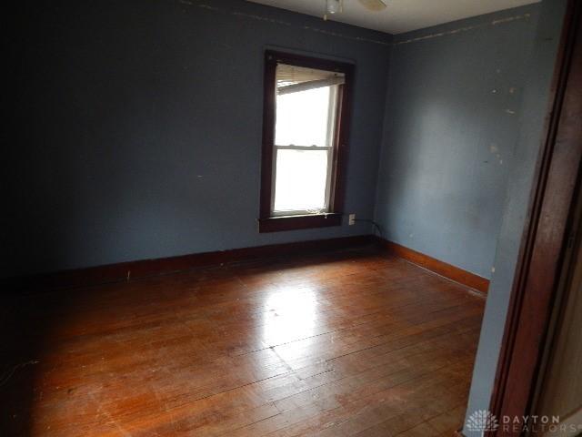 spare room with baseboards and hardwood / wood-style flooring