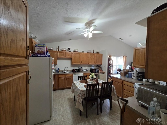 kitchen with white appliances, sink, vaulted ceiling, ceiling fan, and a textured ceiling