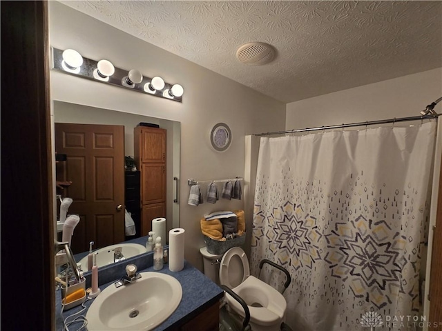 bathroom with vanity, toilet, a textured ceiling, and walk in shower